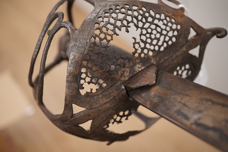 A basket hilted broadsword c.1640, later replacement blade, iron hilt of multi bars with remains of pierced guard, faceted pommel with its original wooden grip, wire covering missing, blade 79cm